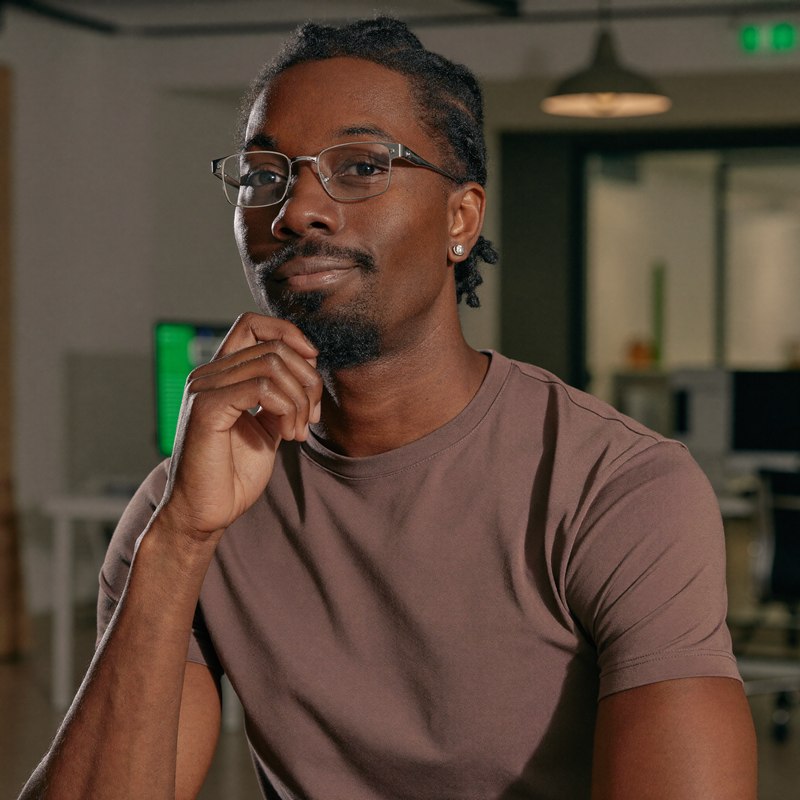 Black man with glasses in a casual tee, founder